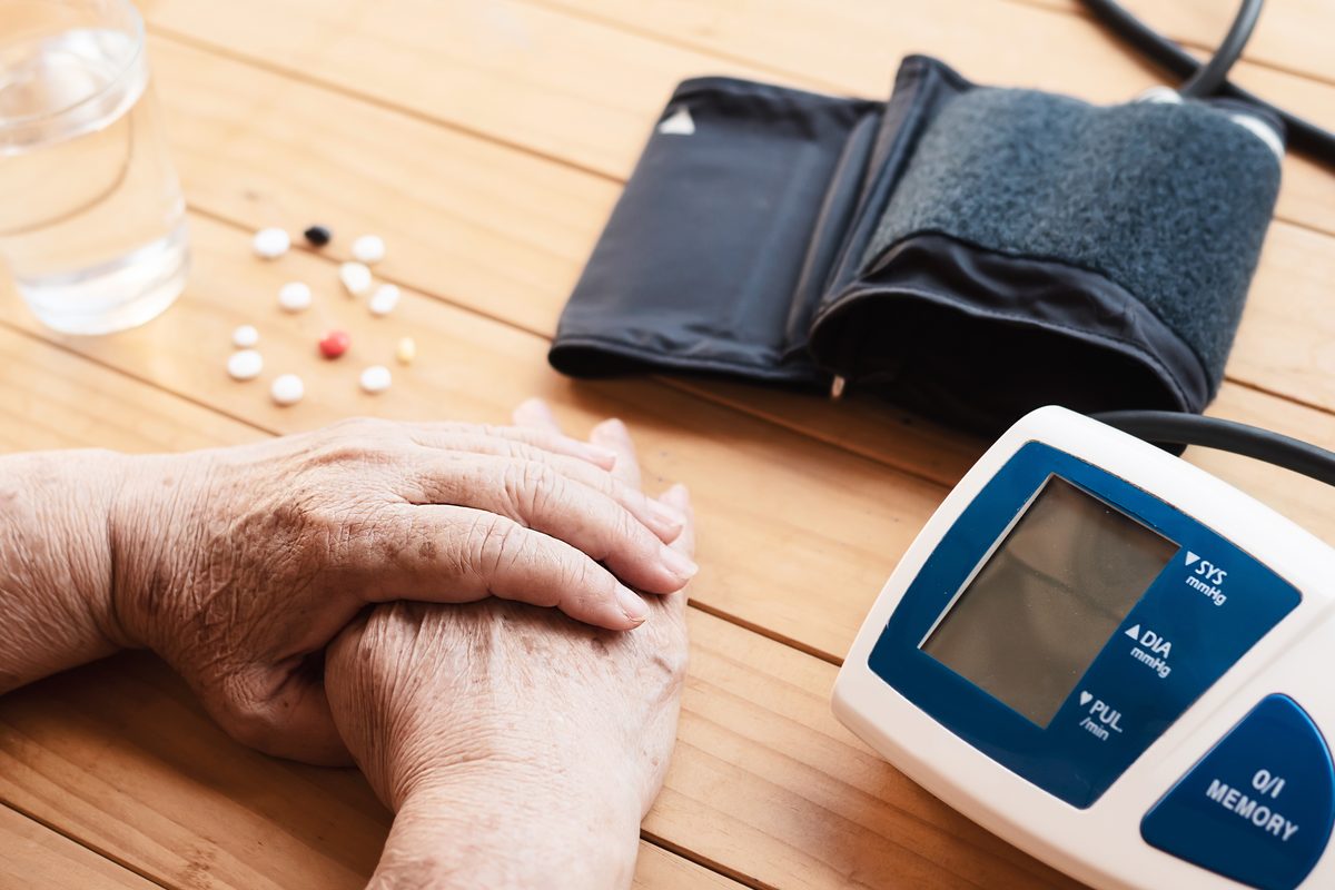 Chronic condition management: a home blood pressure monitor, daily medicines and a glass of water on a kitchen table