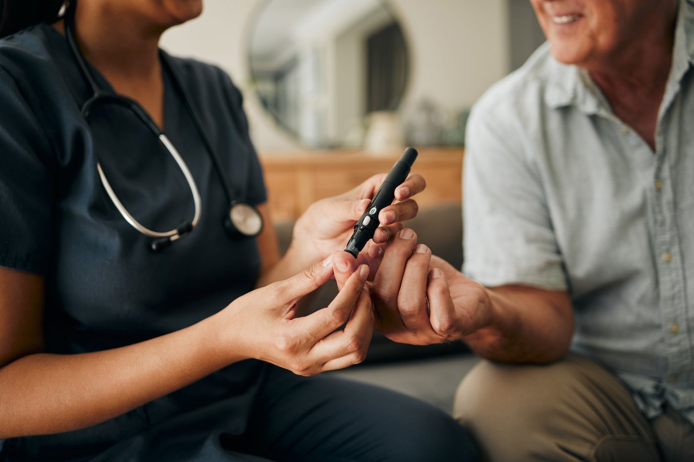 Chronic disease management: a nurse taking a finger-prick blood sugar reading for an older man