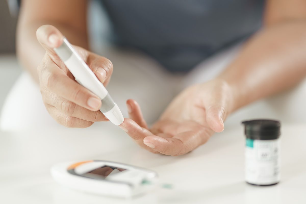 Diabetes review: a person checking their blood glucose level with a lancet and glucose meter