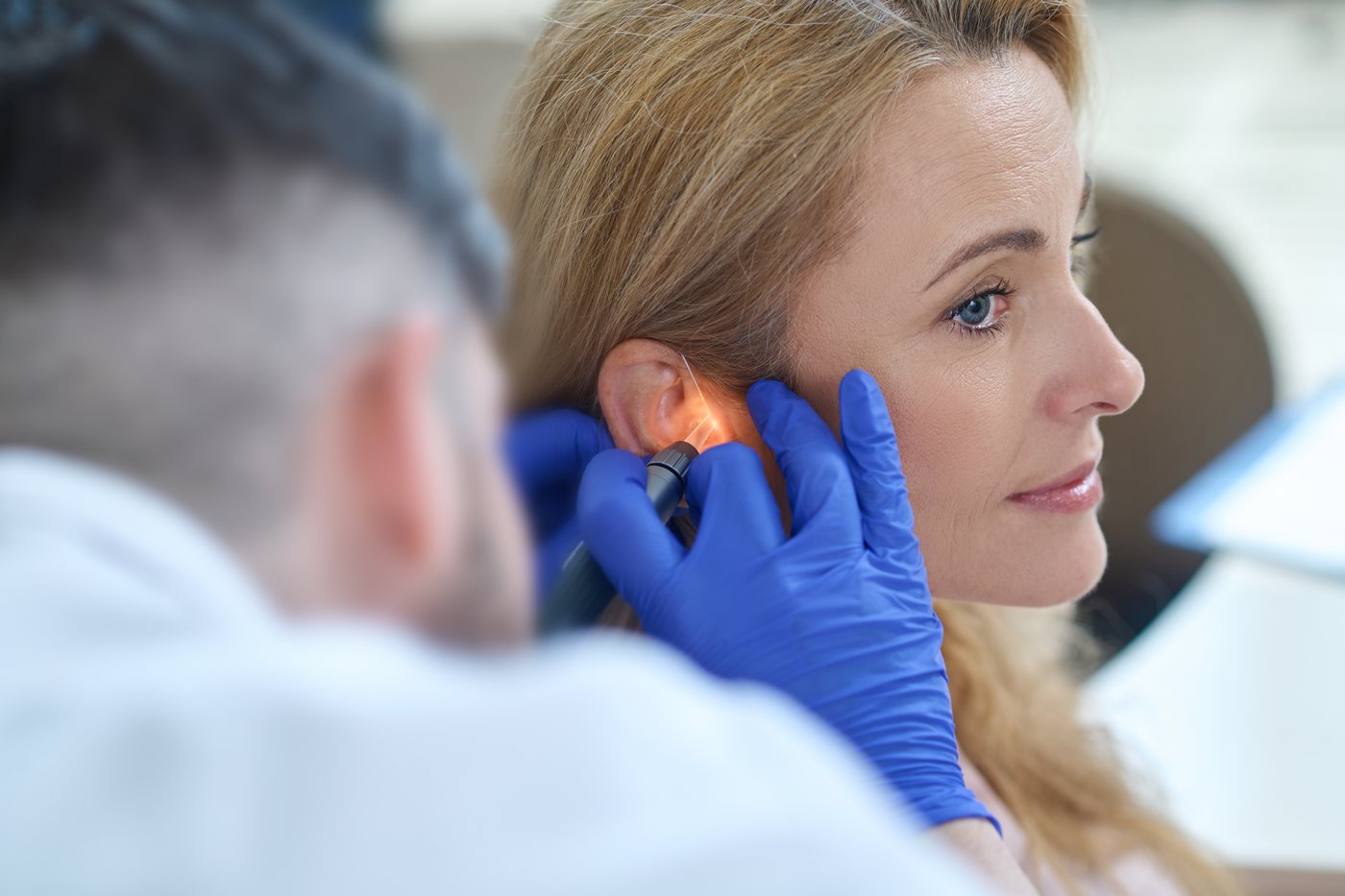 Ear syringing: a clinician examining an ear with an otoscope