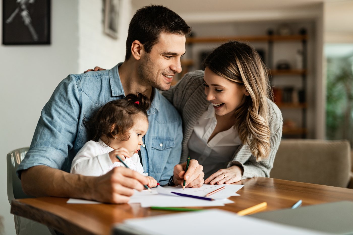 Family planning: parents and a young child drawing together at a table at home