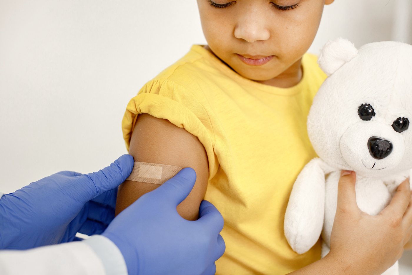 Childhood immunisation: a nurse placing a plaster on a young child's arm after a vaccination