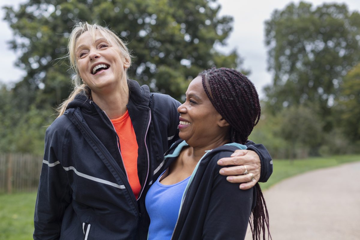 Perimenopause and menopause: two women in their forties walking together outdoors and laughing
