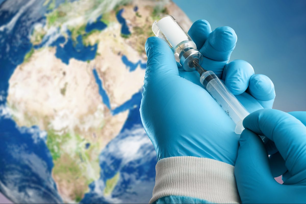 Travel vaccinations: a clinician drawing up a vaccine from a vial, with a globe behind