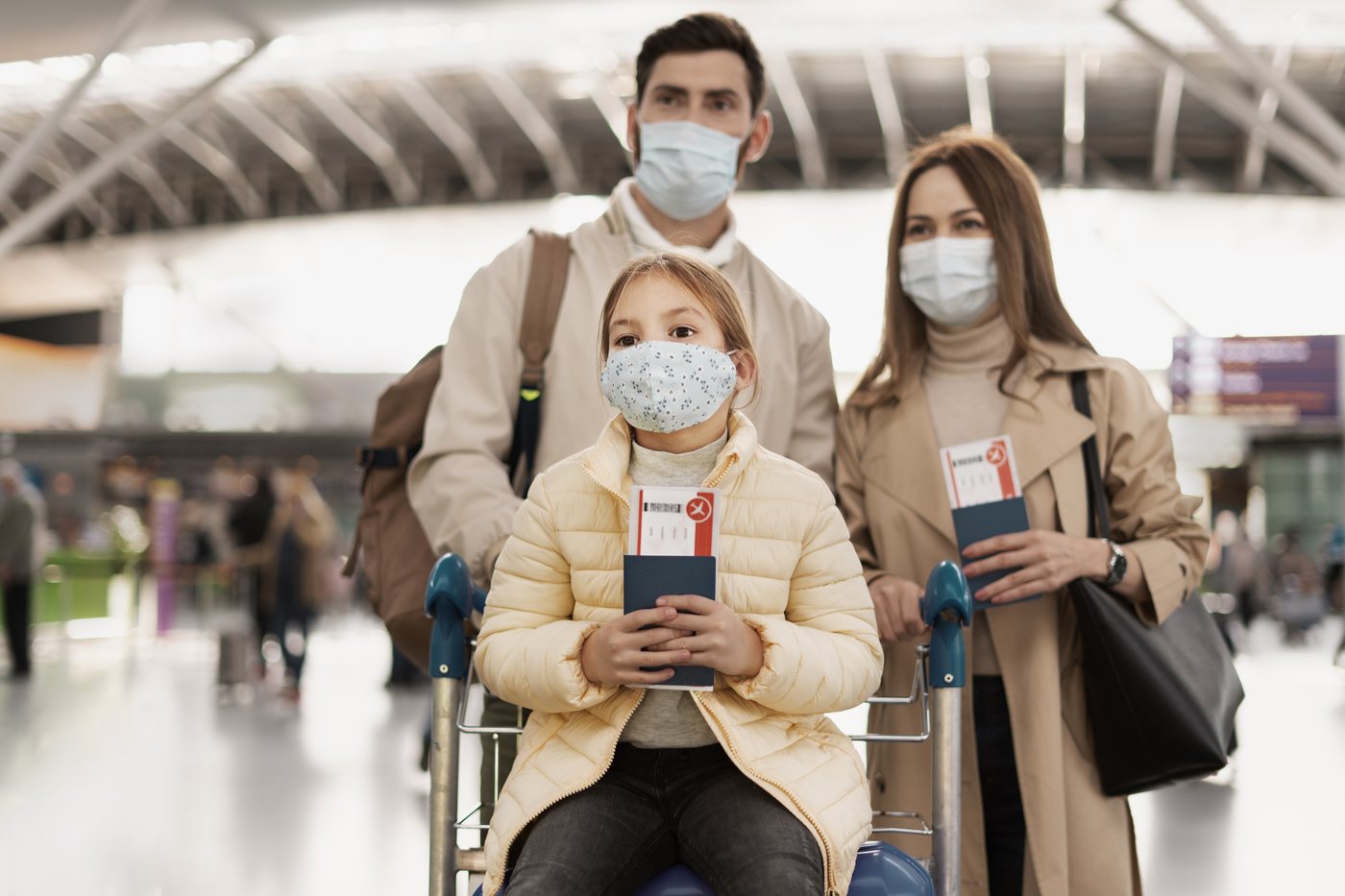 Travel health: a family with passports and boarding passes in an airport departure hall