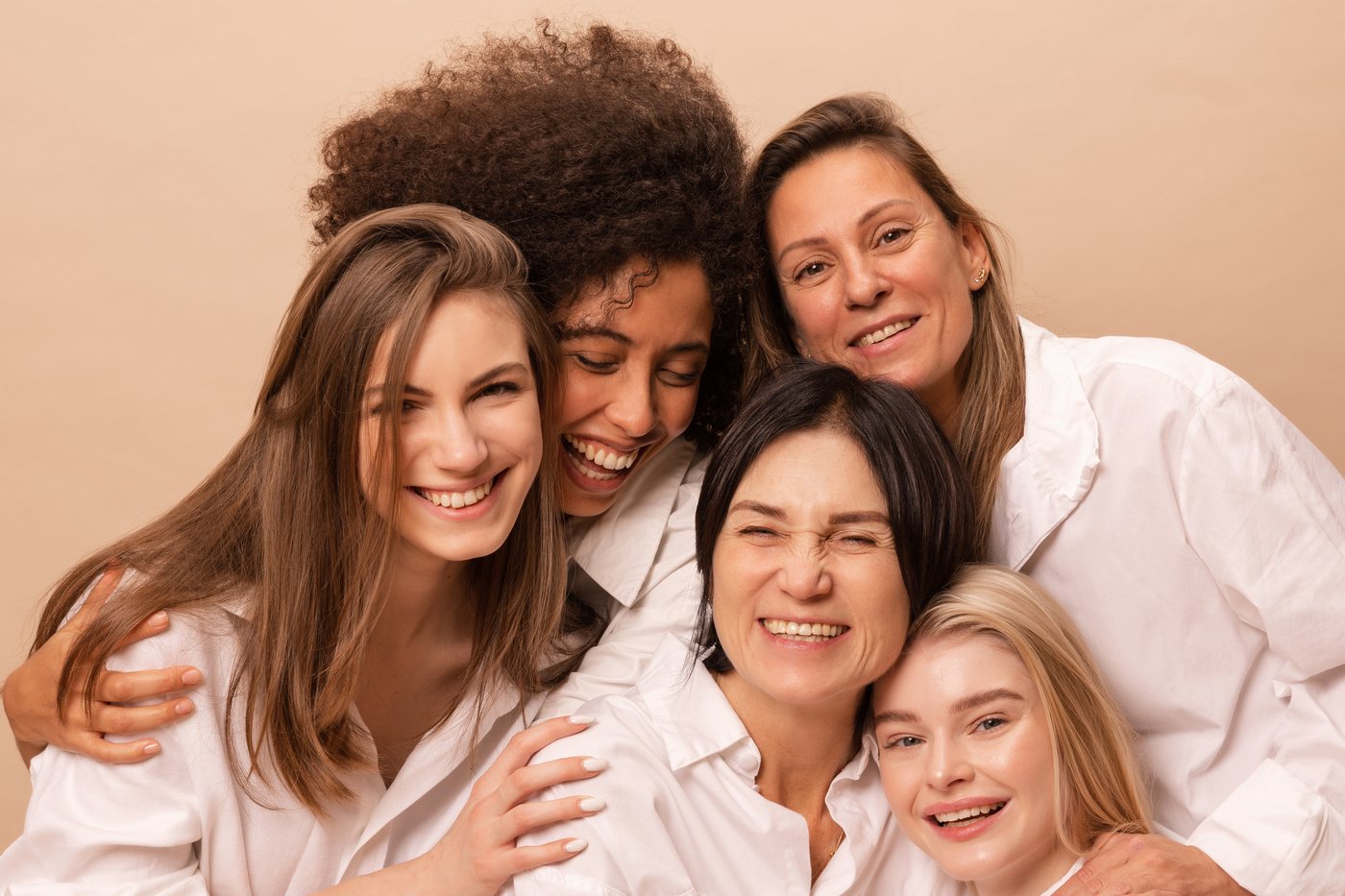 Women's health care at every age: five women of different ages sitting together and laughing